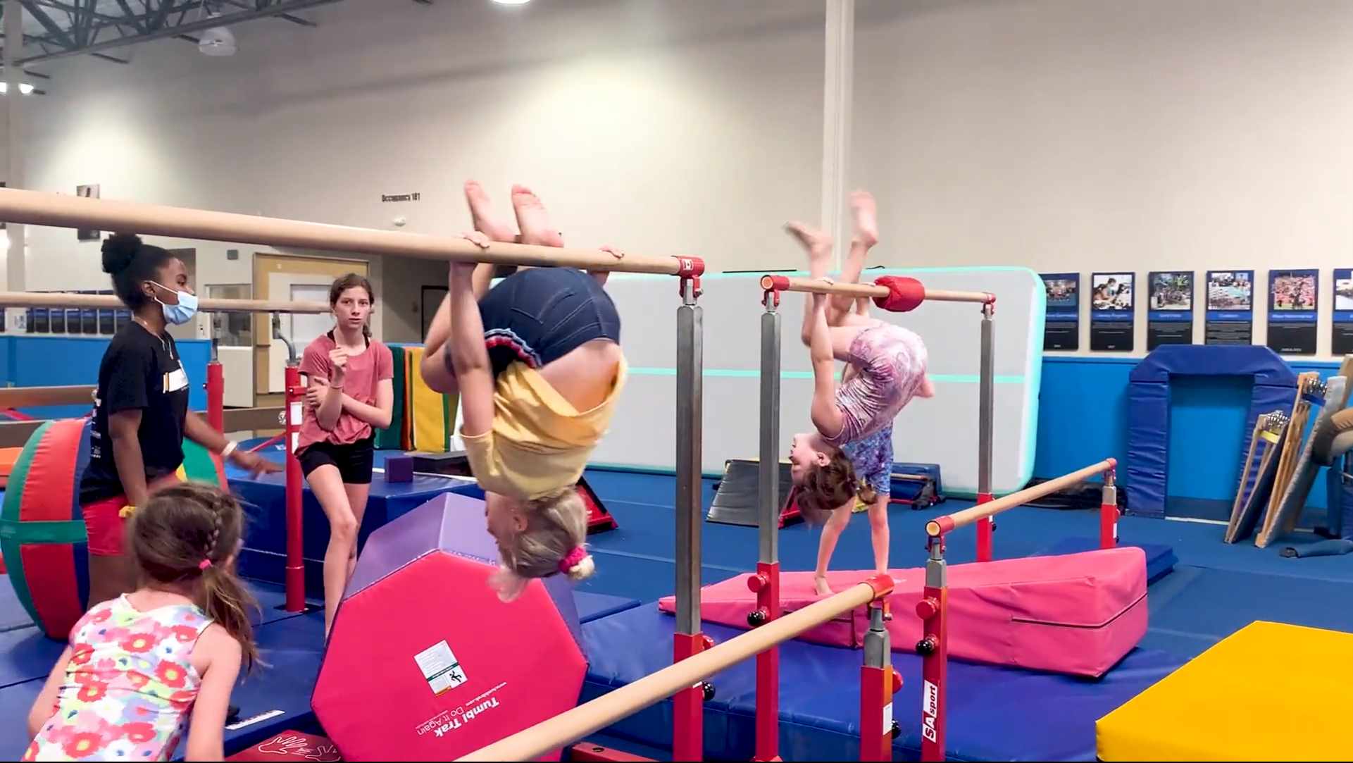 Children hanging upside down on small uneven bars